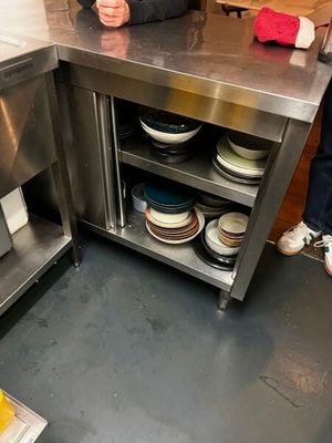 une femme debout derrière un comptoir en acier inoxydable dans une cuisine
