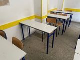 tables and chairs in an empty classroom with a yellow wall