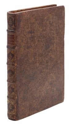 un vieux livre à la couverture brune posé sur une surface blanche