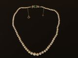 un ensemble composé d'un collier et de boucles d'oreilles en perles blanches sur fond noir
