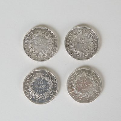 quatre types différents de pièces d'argent sur une surface blanche