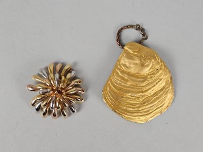 deux bijoux en or et en argent posés sur un fond blanc