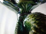 a close up of a green vase with a bird on it