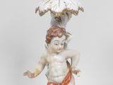 une figurine représentant un garçon tenant un oiseau au-dessus d'un vase