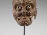 a wooden mask on a stand with a white background