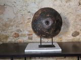 un grand objet en pierre posé sur une table devant un mur de briques