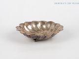 a silver plate with a shell on it on a white surface