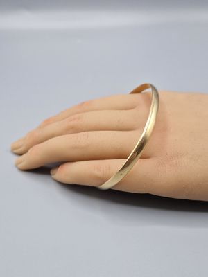 the hand is holding a gold bracelet on it ' s arm