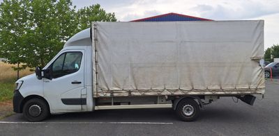 un camion blanc avec une bâche à l'arrière, garé sur un parking