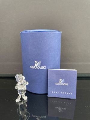 un petit ours en cristal posé à côté d'une boîte bleue