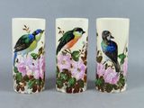 three vases with birds painted on them sitting on a table