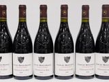 six bottles of wine are lined up in a row on a white surface