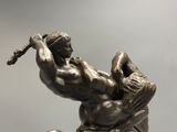 bronze statue of a man holding a baseball bat on top of a ball