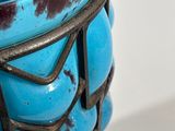 a close up of a blue vase with a metal handle