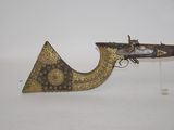 a close up of a gun on a stand on a white surface