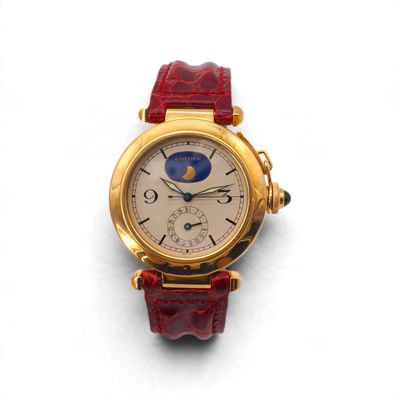 une photo d'une montre-bracelet en or avec un bracelet en cuir rouge