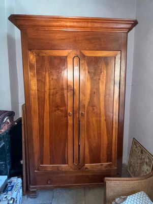a wooden armoire in the corner of a room with a wicker chair