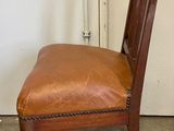 a brown leather chair with a wooden back and seat