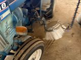 a blue tractor with a broom on the front of it