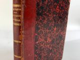 un vieux livre à la couverture rouge posé sur une table blanche