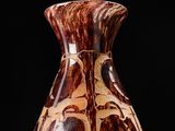 a brown and white vase sitting on a black surface