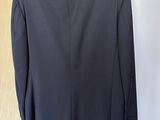 a black jacket hanging on a hanger in front of a wooden door