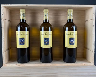 three bottles of wine sit in a wooden box on a table