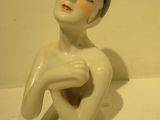 a white figurine of a woman sitting on a table
