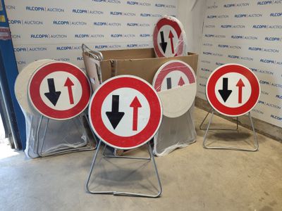 many signs that are sitting on the ground in front of a wall