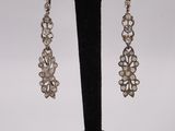 a pair of earrings on a black stand with a white background