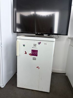 un réfrigérateur blanc sur lequel est posée une télévision, dans une cuisine