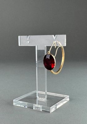 clear acrylic jewelry display stand with a pair of earrings on it