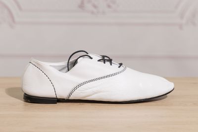 white leather shoes with black laces on a wooden table