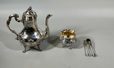 une théière en argent et une cuillère en argent posées sur une table blanche