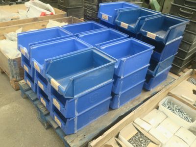 de nombreux bacs bleus empilés sur une palette dans un entrepôt