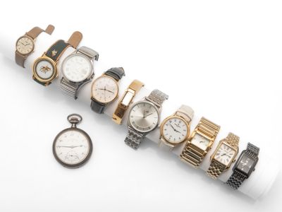 de nombreuses montres et une montre de poche posées sur une surface blanche
