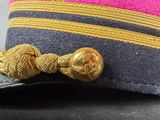 a pink hat with a gold button on it