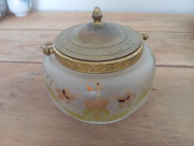 a glass jar with a gold lid sitting on a wooden table