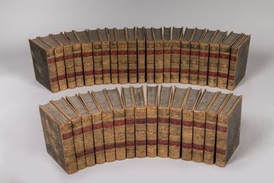 several old books are stacked on top of each other on a white surface