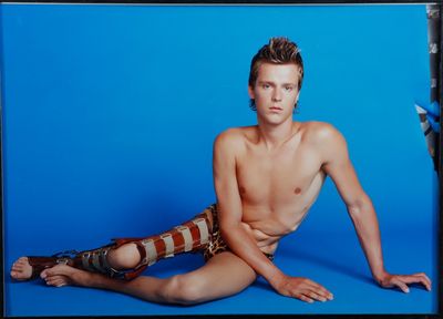a shirtless man sitting on the floor with his hands on his hips