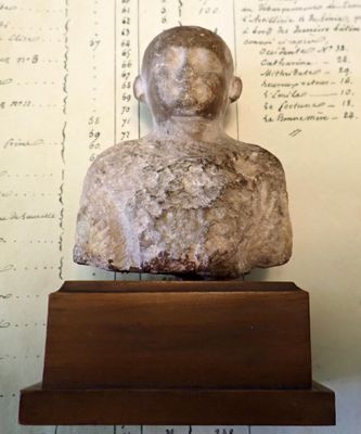 a stone statue of a man sitting on top of a wooden stand