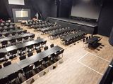 un grand auditorium équipé de tables et de chaises ainsi que d'un écran de projection