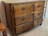 a wooden dresser with drawers and a chair in a room