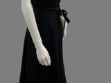 a mannequin wearing a black dress with a bow around the neck