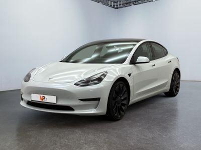 a white tesla model 3 parked in a white room