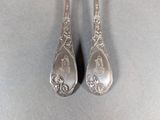 two silver spoons sitting on top of a table next to each other