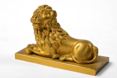 "Lion couché tenant sous sa patte une sphère" en bronze doré…