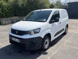 la camionnette blanche est garée sur un parking avec des arbres en arrière-plan
