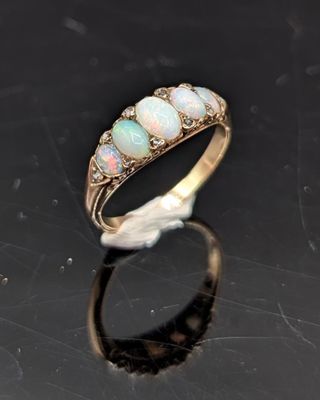 une bague en oplite et diamant posée sur un fond noir