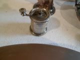 un moulin à poivre en argent posé sur une table à côté d'une assiette de nourriture